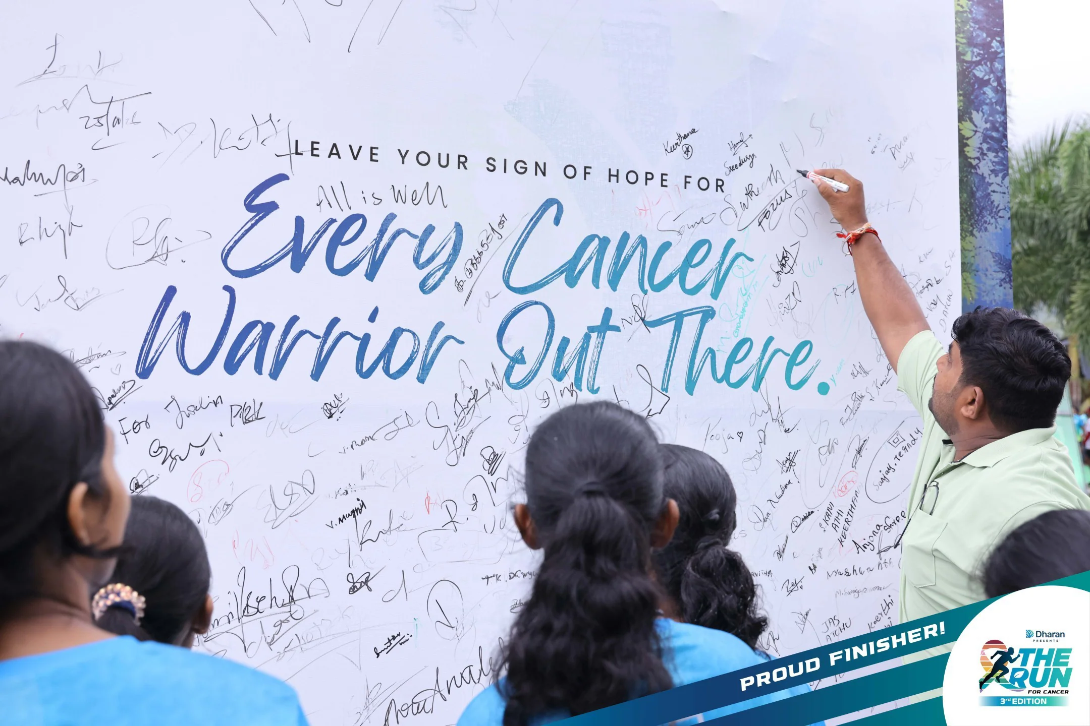 A participant writes a message of hope for cancer warriors on the physical event wall.