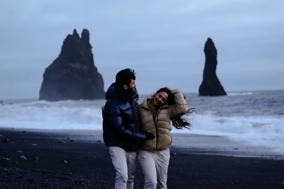 Couple on Reynisfjara black sand beach with sea stacks