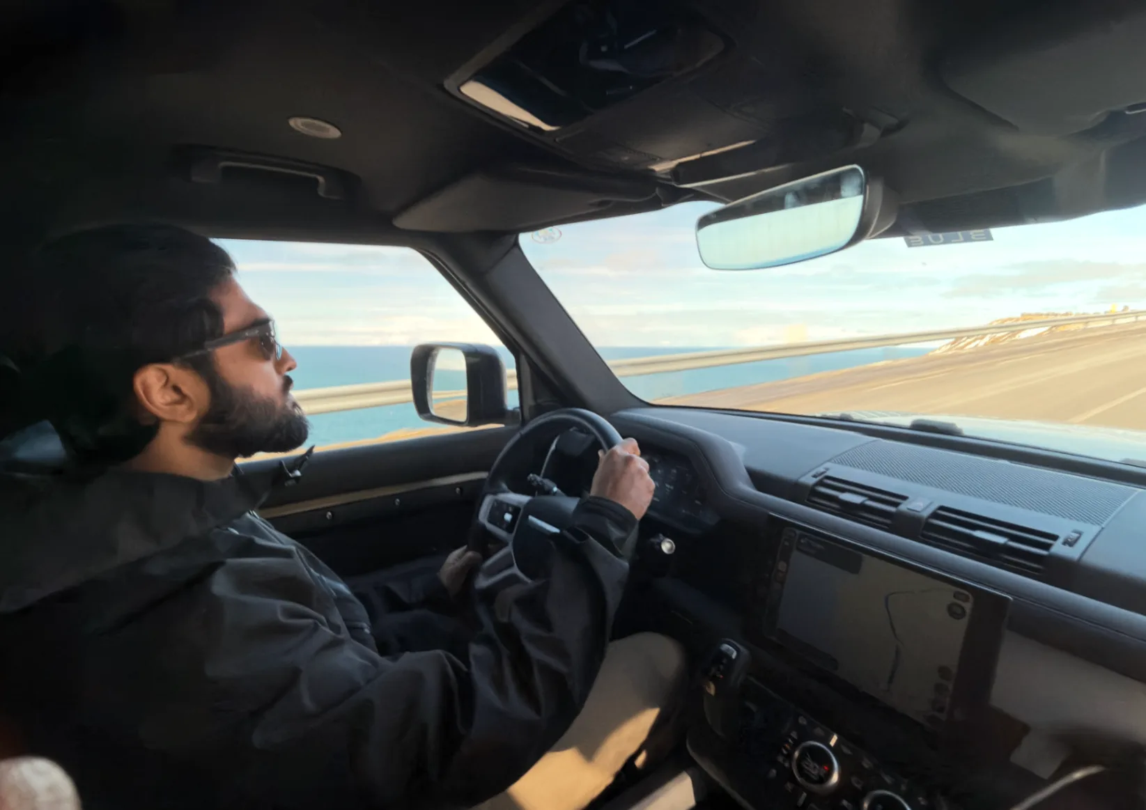 Driver at the wheel of a Land Rover Defender at golden hour